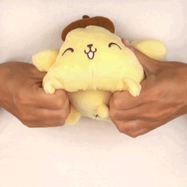 A person affectionately clutching a whimsical yellow TeeTurtle Reversible Pompompurin Plushie from Sanrio.