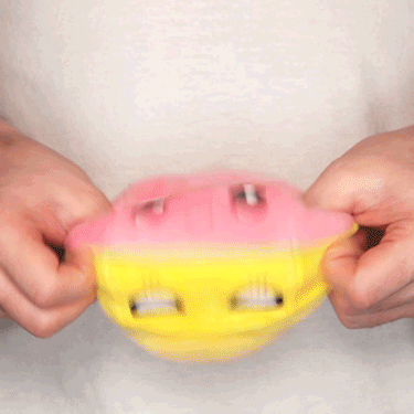 A person holding a TeeTurtle Reversible Ball Plushie (Yellow + Pink) by TeeTurtle.
