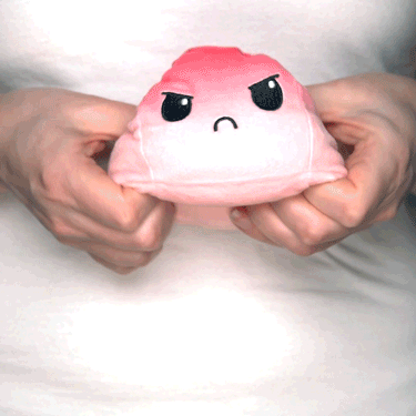 A woman holding a TeeTurtle Reversible Ball Plushie (Pink + Light Pink) toy.