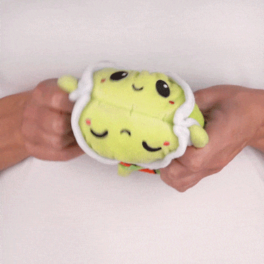 A person holding a TeeTurtle Reversible Turtle Plushie (Strawberries & Flowers Shell).