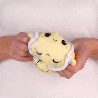 A person holding a TeeTurtle Reversible Turtle Plushie (Lemons & Flowers Shell).