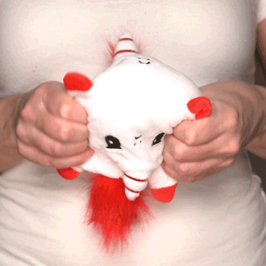 A woman holding a TeeTurtle Reversible Unicorn Plushie (Candy Cane Horn).