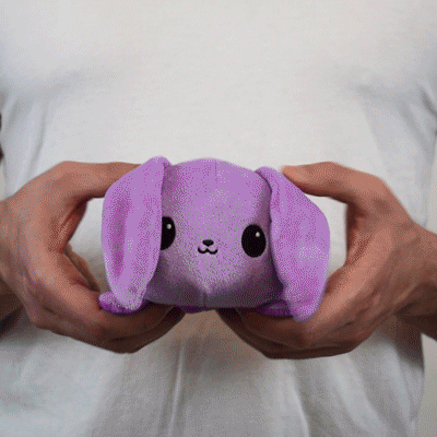 A man holding a TeeTurtle Reversible Bunny Plushie (Purple + Light Purple)