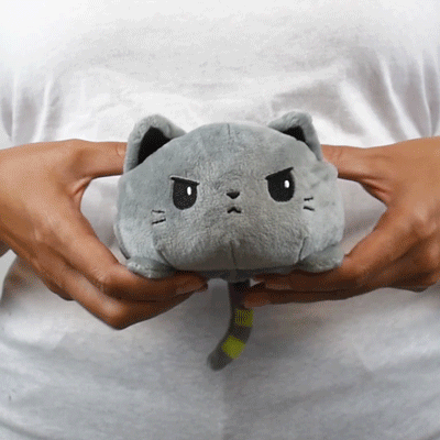 A person holding a TeeTurtle Reversible Catzilla Plushie (Glow) from TeeTurtle.