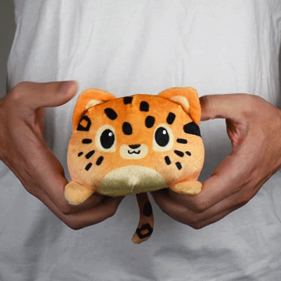 A person holding a small stuffed animal - a TeeTurtle Reversible Leopard Plushie from TeeTurtle.