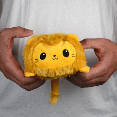 A person holding a TeeTurtle Reversible Lion Plushie (Brown) stuffed animal.