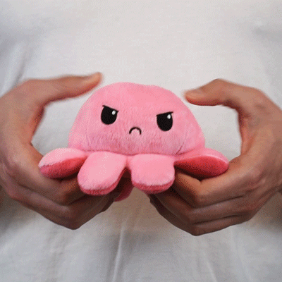 A person holding a TeeTurtle Reversible Octopus Plushie (Pink RAGE).
