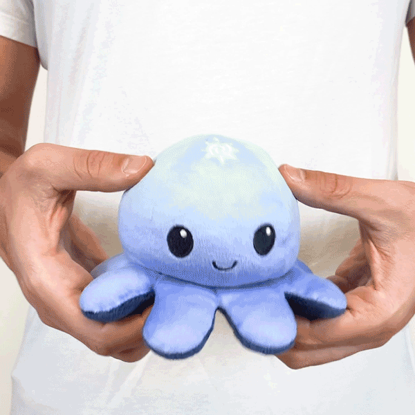 A person holding a TeeTurtle Reversible Octopus Plushie (Night + Day).