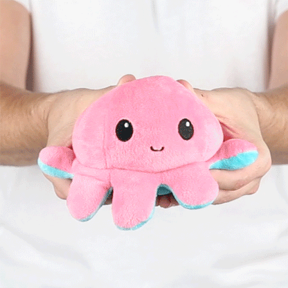 A person holding a TeeTurtle Reversible Octopus Plushie (Aqua + Pink).