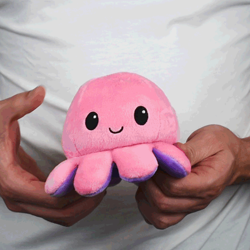 A person holding a TeeTurtle Reversible Octopus Plushie (Purple + Pink).