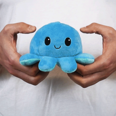 A person holding a TeeTurtle Reversible Octopus Plushie (Light Blue + Blue).