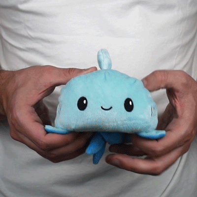 A person holding a TeeTurtle Reversible Shark Plushie.