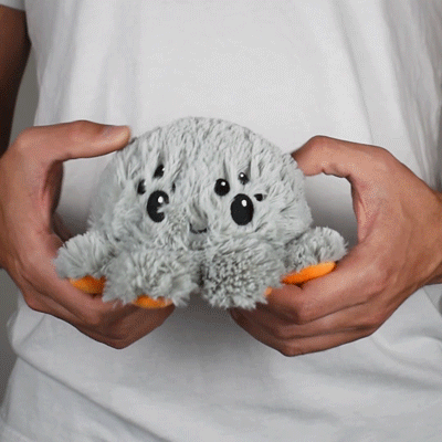A person holding a TeeTurtle Reversible Spider Plushie (Jack-o-Lantern).