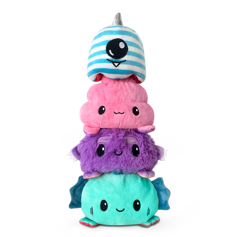 A stack of TeeTurtle Reversible Fuzzy Monster Plushies sitting on top of each other.