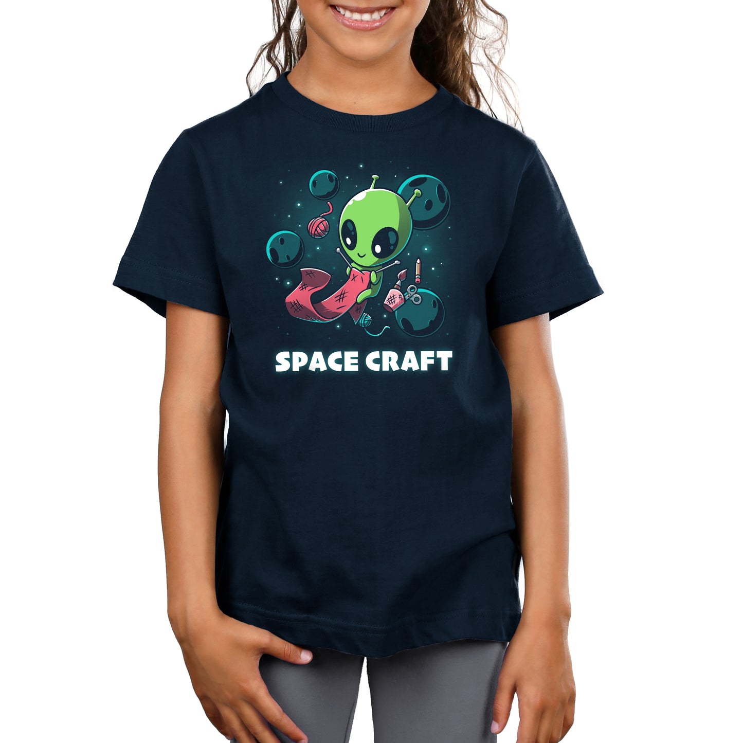 A young girl wearing a navy blue t-shirt with a TeeTurtle Space Craft design.
