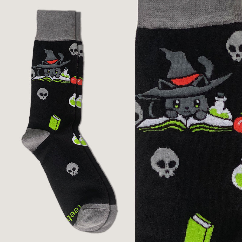 A pair of Spellbound Socks by TeeTurtle, featuring a black sock with a cat in a witch hat and skulls, offering comfort and fit.