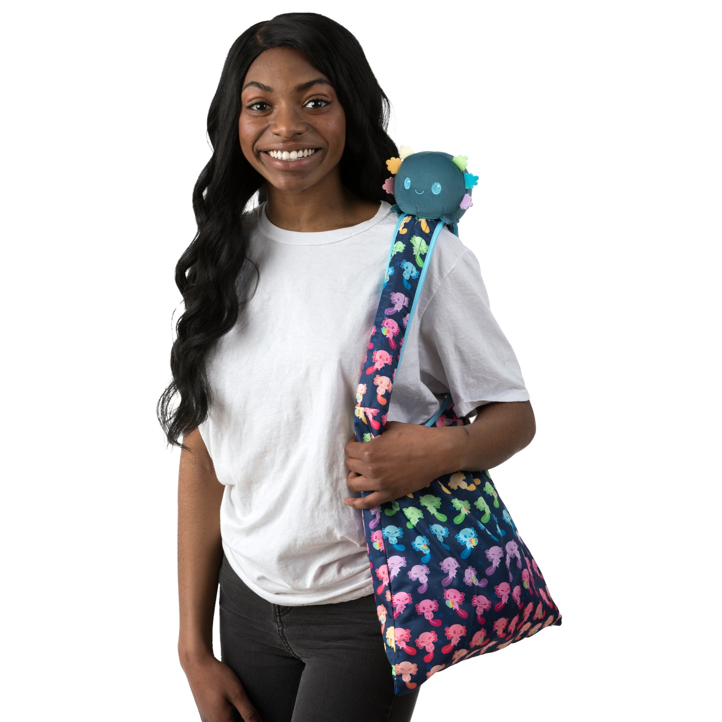 A woman holding a Plushiverse Rainbow Axolotl Plushie Tote Bag by TeeTurtle with a unicorn on it.