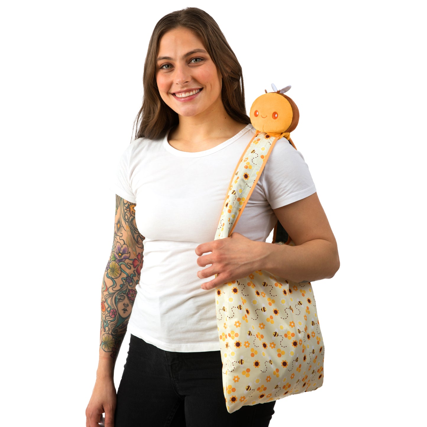 A woman with tattoos showcasing a TeeTurtle Plushiverse Honeybee Plushie Tote Bag.
