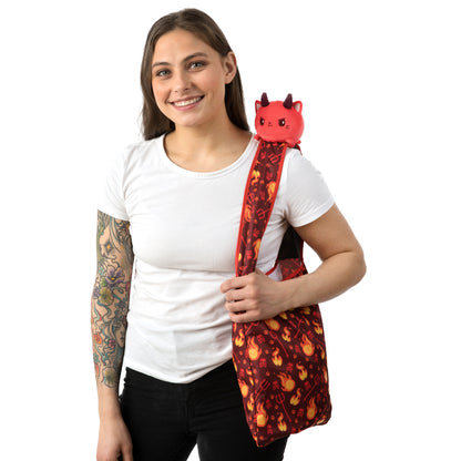 A woman with tattoos holding a TeeTurtle Plushiverse Devilish Kitty Plushie Tote Bag.