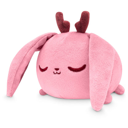 A pink TeeTurtle Plushiverse Fearsome Jackalope plush toy rabbit with long ears and a content, sleeping facial expression, isolated on a white background.