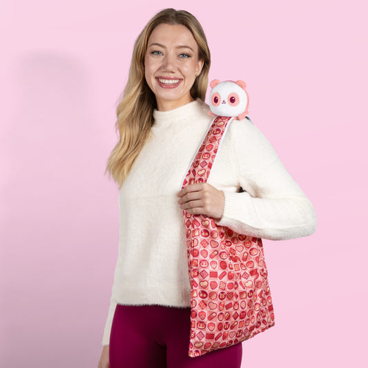 A woman carrying a TeeTurtle Plushiverse Choco-Panda Plushie Tote Bag with a plush owl inside.