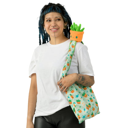 A woman with dreadlocks holding a TeeTurtle Plushiverse Succulent Garden Plushie Tote Bag.