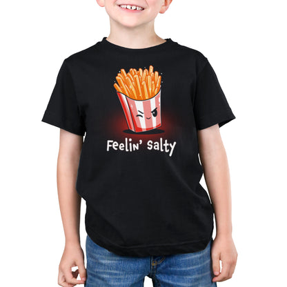 A boy in a black t-shirt made of super soft ringspun cotton with the TeeTurtle logo and the words "Feelin' Salty" printed on it.
