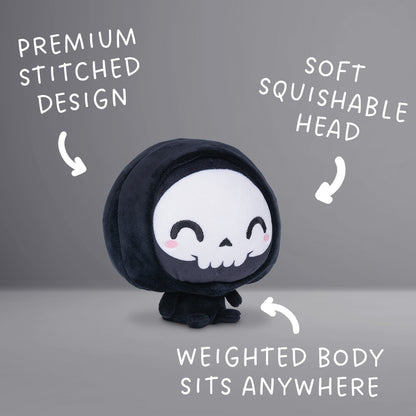 Cloudheads: 5" Grim Reaper (Grim) - A black hooded plush grim reaper with a white skull face, black embroidered eyes and mouth, and small pink cheeks, shown on a plain white background. Text with the phrases "Premium stitched design," "soft squishable head" and "weighted body sits anywhere."