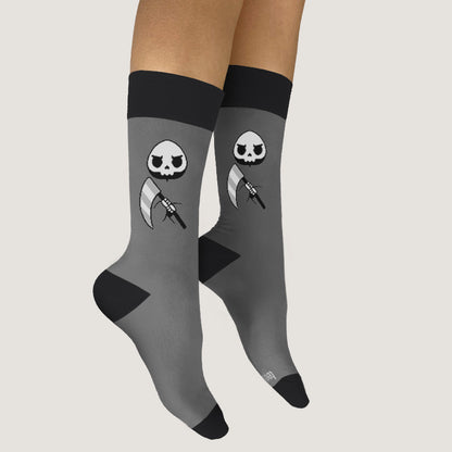 A pair of Grim Reaper socks by TeeTurtle, featuring a skull and axe design, perfect for friends who appreciate a touch of edginess in their footwear.