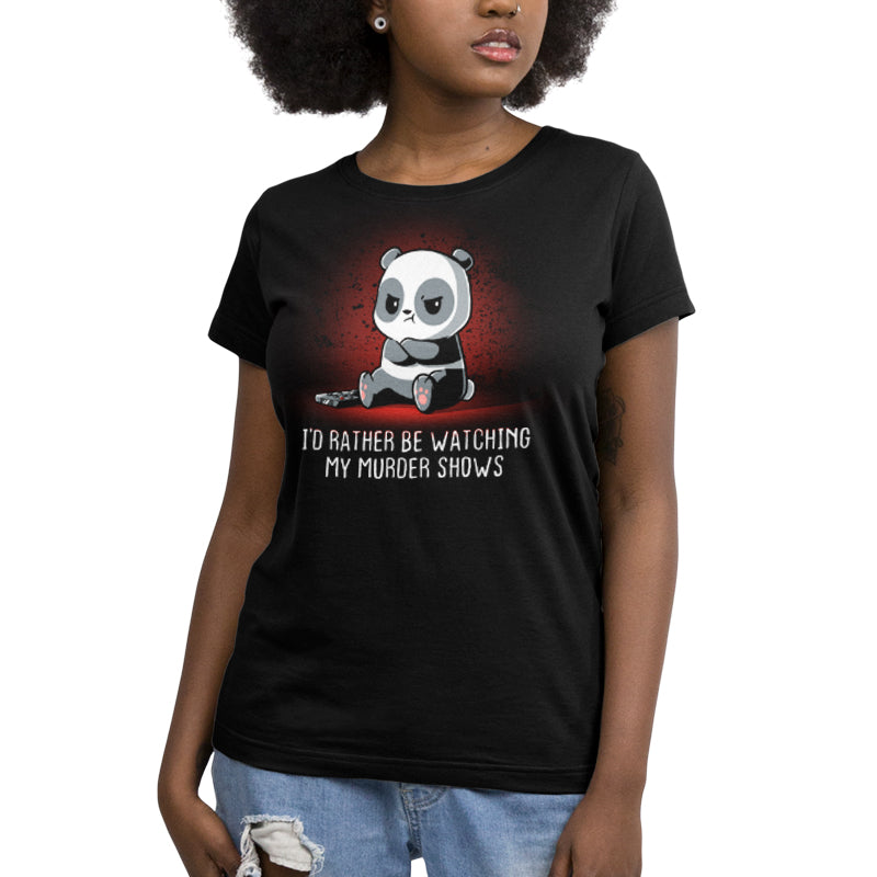 A woman wearing a black t-shirt with the product name "I'd Rather Be Watching My Murder Shows" from the brand name TeeTurtle, while watching her true crime podcasts.