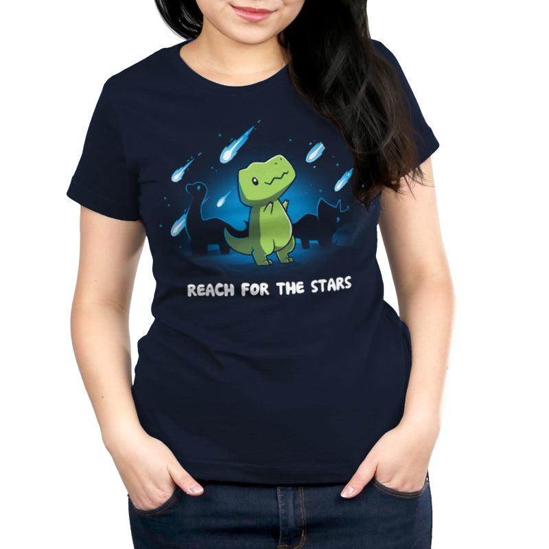 Person wearing a navy blue monsterdigital Reach For The Stars tee made of super soft ringspun cotton, featuring a cartoon dinosaur and shooting stars, captioned “REACH FOR THE STARS.”