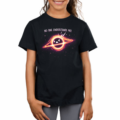 Young girl wearing a black Monsterdigital Black Hole Angst unisex tee featuring a graphic of a planet with a face inside a ring, and the text "no one understands me!" against a starry background.