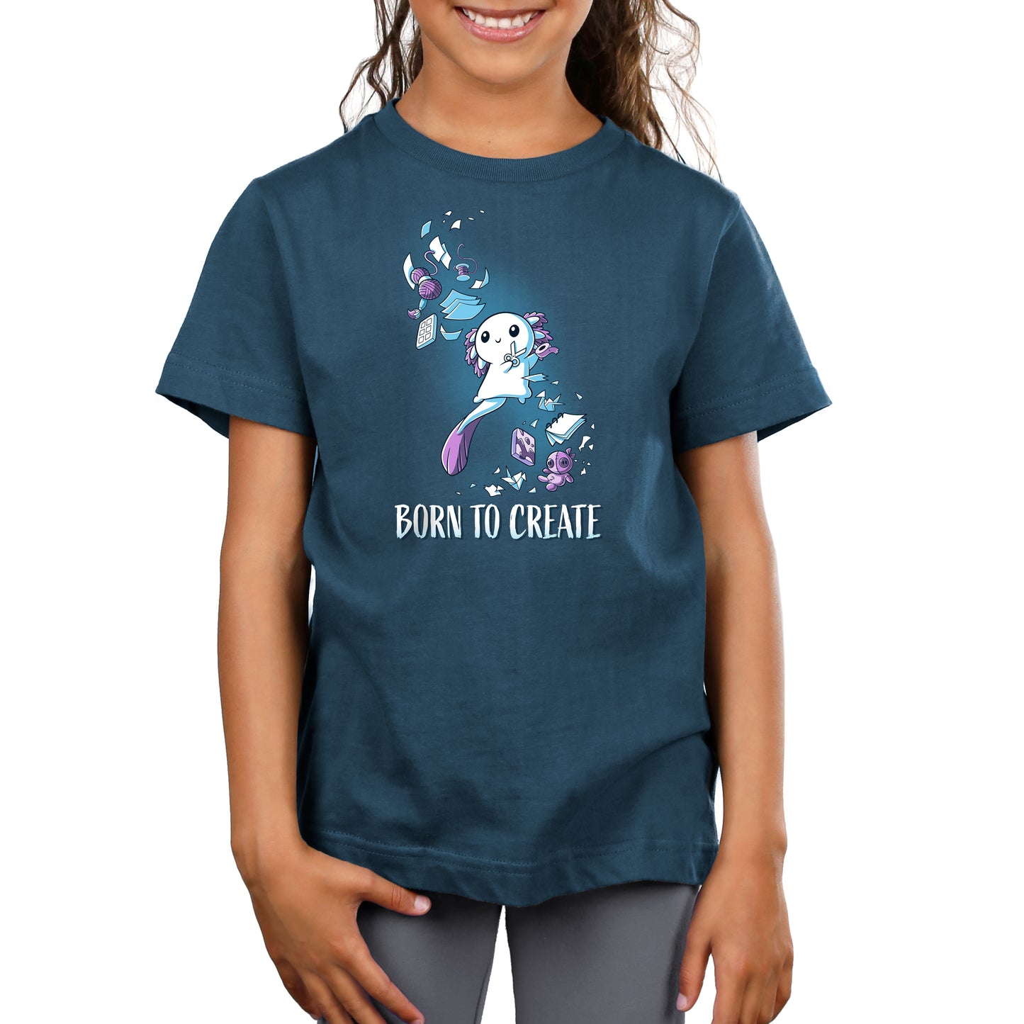 A child wearing a denim blue T-shirt crafted from super soft ringspun cotton, featuring an illustration of a white animal character surrounded by creative elements and the text "Born to Create" by monsterdigital.