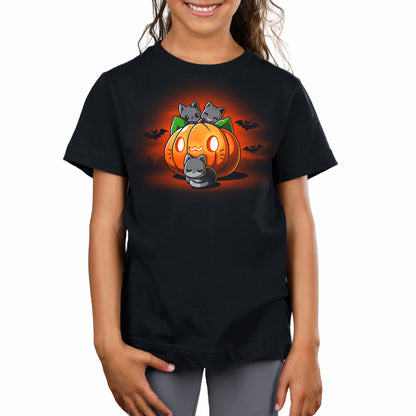 A girl wearing a TeeTurtle Cat O'Lantern black t-shirt with an image of a pumpkin.