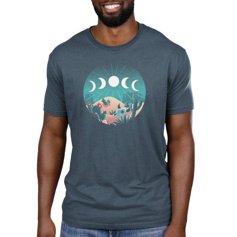 Premium Cotton T-shirt - A person wearing a monsterdigital Desert Moons apparel in Denim Blue, crafted from soft Ringspun Cotton, showcasing an illustration of a desert scene with cacti, mountains, and phases of the moon above the landscape.