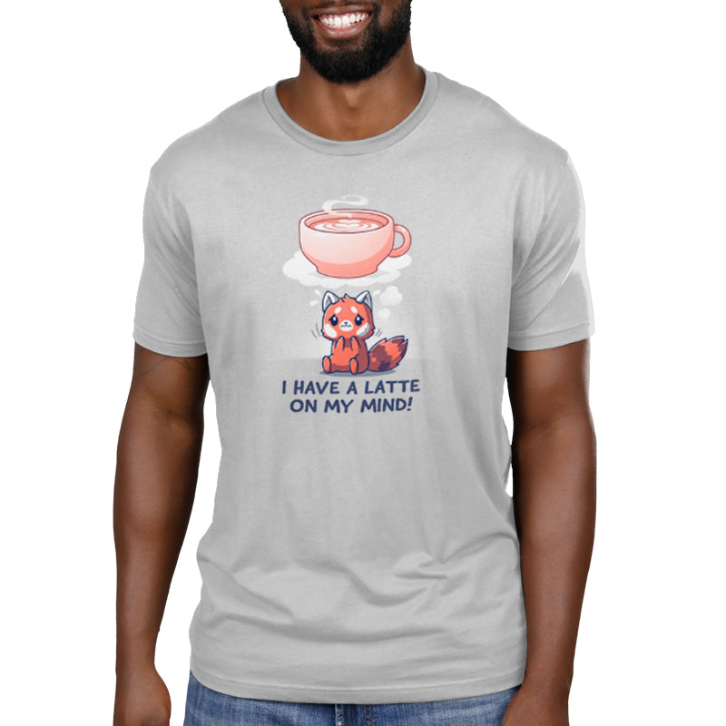 Person wearing a light gray unisex T-shirt made of super soft ringspun cotton with an illustration of a coffee cup and cute red panda. Text on the shirt reads, "I Have a Latte on My Mind!" The T-shirt is from the brand monsterdigital.