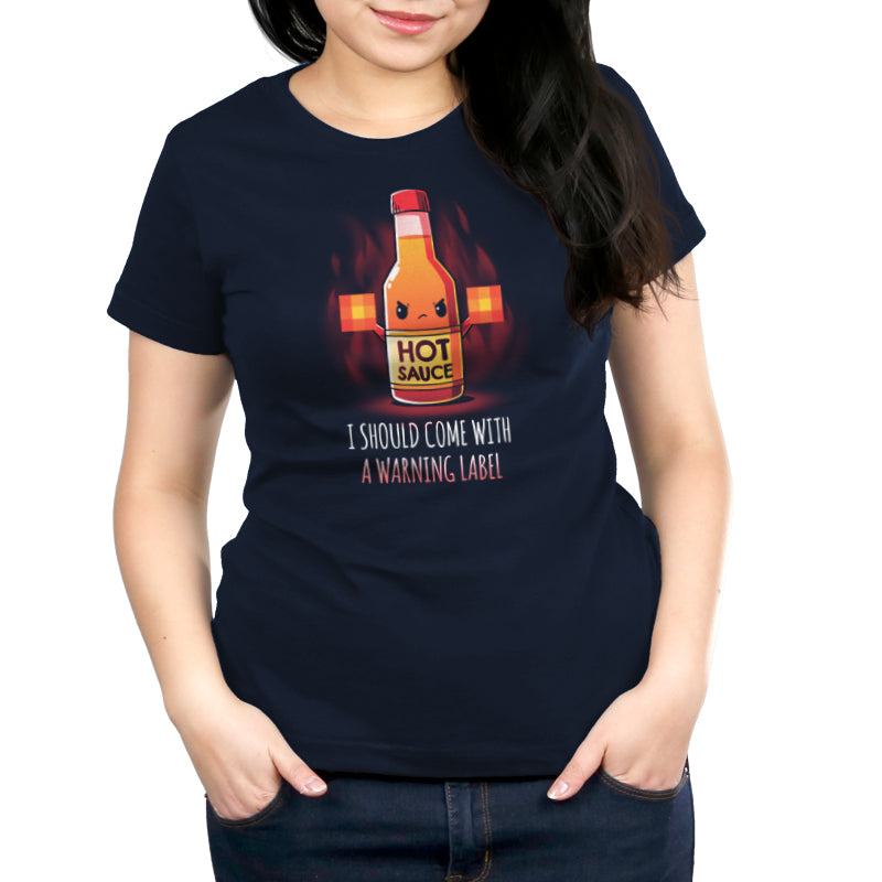 A woman wearing a navy blue t-shirt with an I Should Come With a Warning Label hot sauce bottle by TeeTurtle.