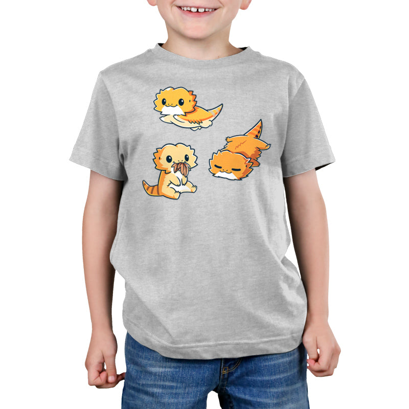 Premium Cotton T-shirt - A child wearing a super soft ringspun cotton Lil' Bearded Dragons apparel by monsterdigital with colorful cartoon depictions of a seated platypus, a flying platypus, and a sleeping platypus in various poses.