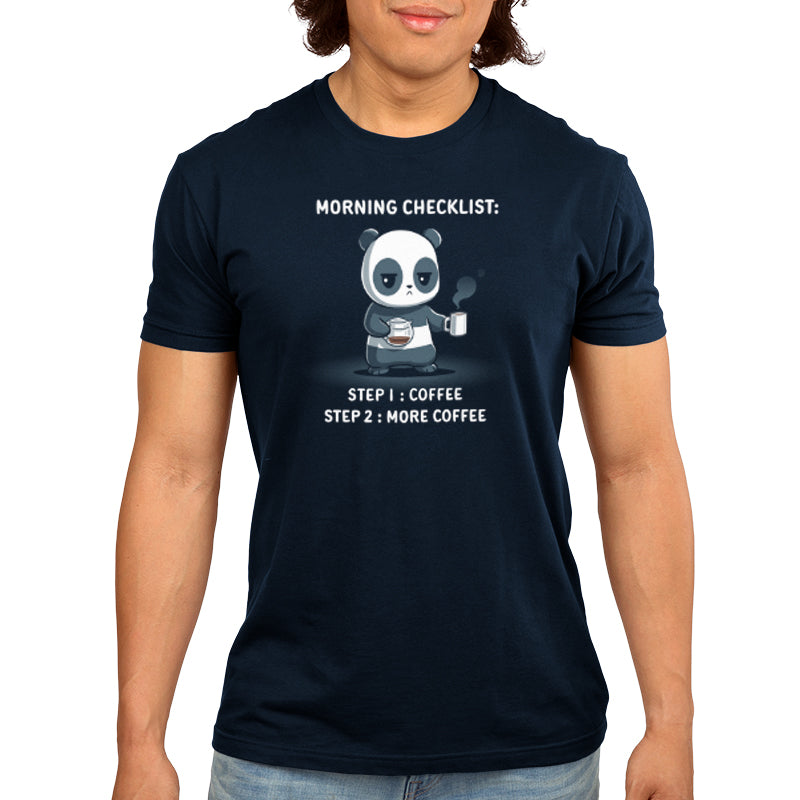 Person wearing a super soft ringspun cotton navy blue t-shirt with an illustration of a panda holding a coffee cup and text that reads, "Morning Checklist: Step 1: Coffee. Step 2: More Coffee," called the Morning Checklist by monsterdigital.