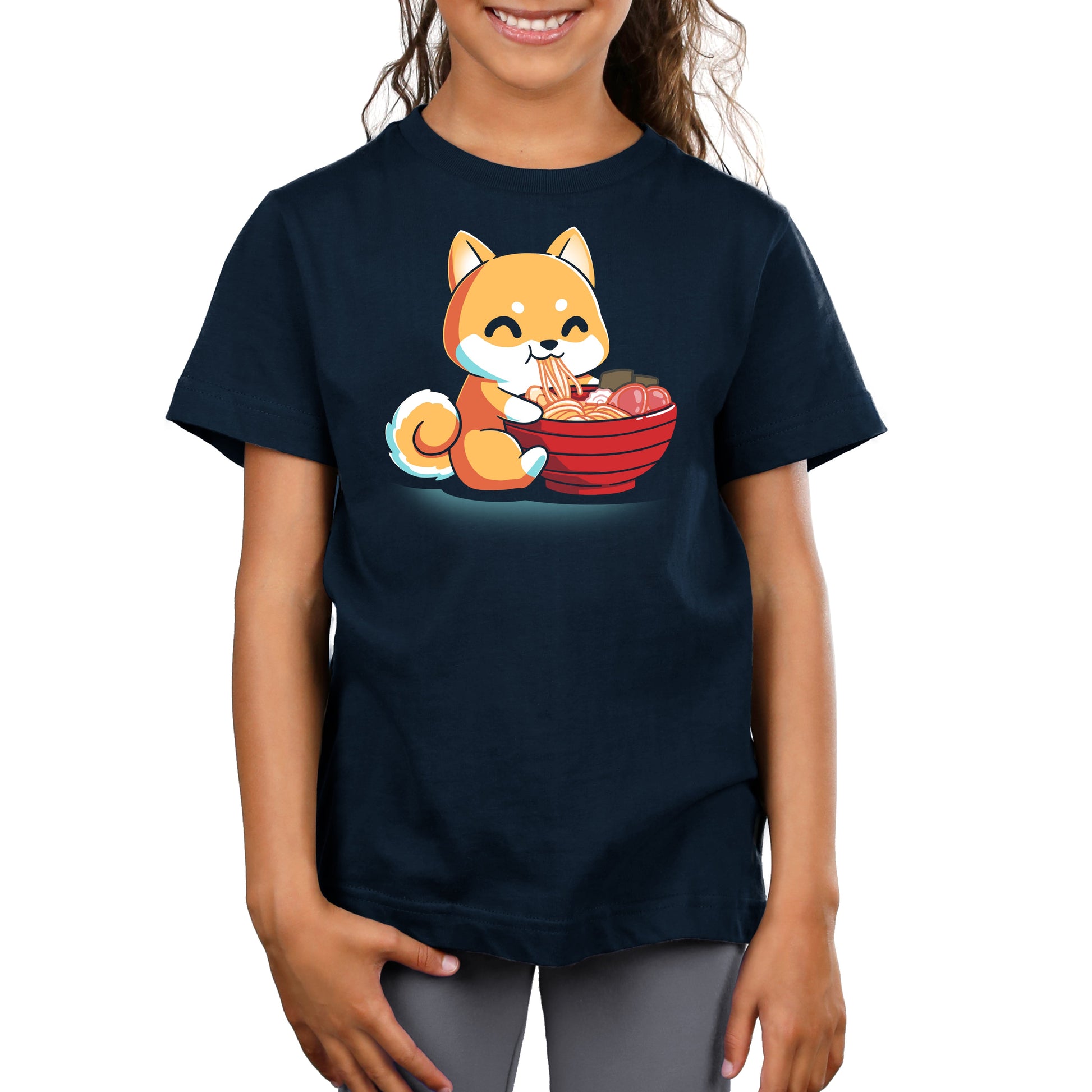 Young girl wearing a navy blue t-shirt made from Super Soft Ringspun Cotton, featuring a cartoon Ramen Shiba eating noodles from a red bowl by monsterdigital.