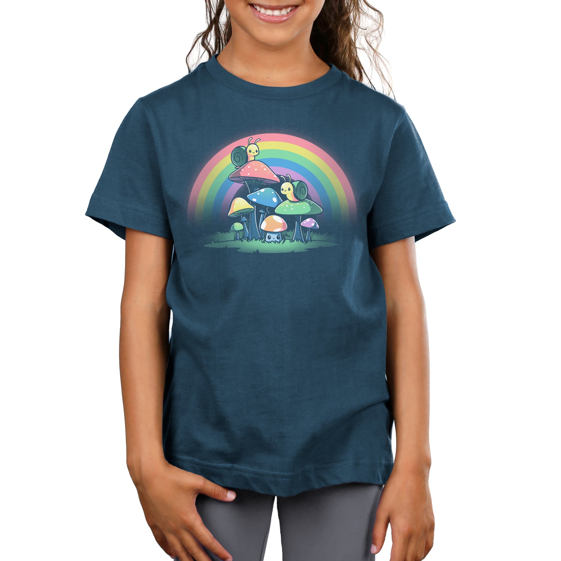 A girl wearing a blue t-shirt with a rainbow on it, featuring TeeTurtle's Snails and Mushrooms design.