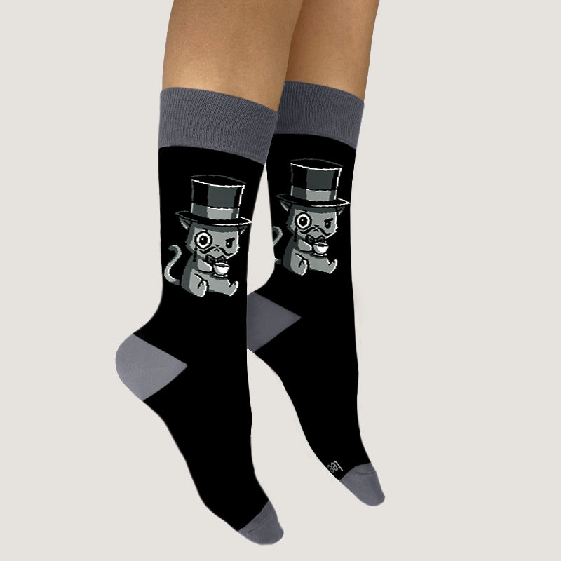 A woman wearing TeeTurtle's How A-mew-sing Socks with her social creature friend, a cat in a top hat.