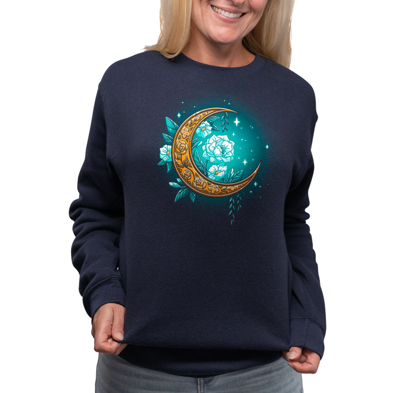 A woman wearing a TeeTurtle Floral Moon sweatshirt with a floral moon design on a navy blue background.