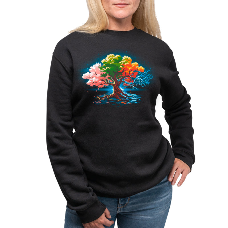 A woman wearing a TeeTurtle Seasonal Tree sweatshirt, featuring a colorful tree, symbolizing the change of seasons.