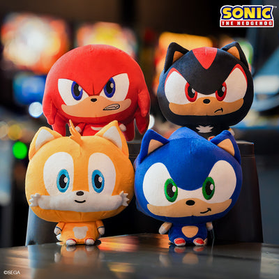 Sonic the Hedgehog Cloudheads Bundle - these plushie have big heads and tiny bodies. Knuckles, Shadow, Tails and Sonic are sitting on a table with blurry arcade machines behind them. 