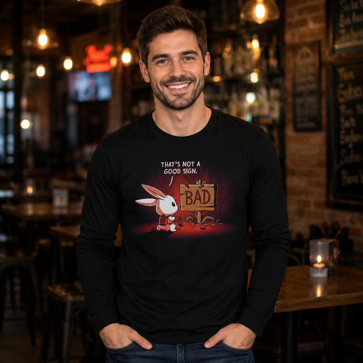 Long Sleeve T-shirt_TeeTurtle That's Not a Good Sign black t-shirt featuring an adventurous bunny looking at a wooden sign with the word "bad" on it.