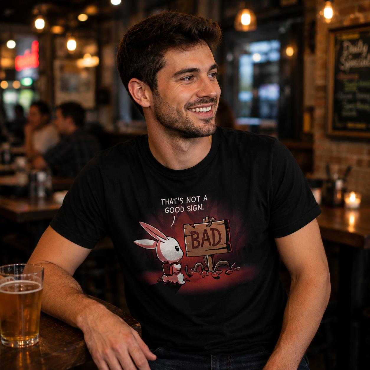 Premium Cotton T-shirt_TeeTurtle That's Not a Good Sign black t-shirt featuring an adventurous bunny looking at a wooden sign with the word "bad" on it.