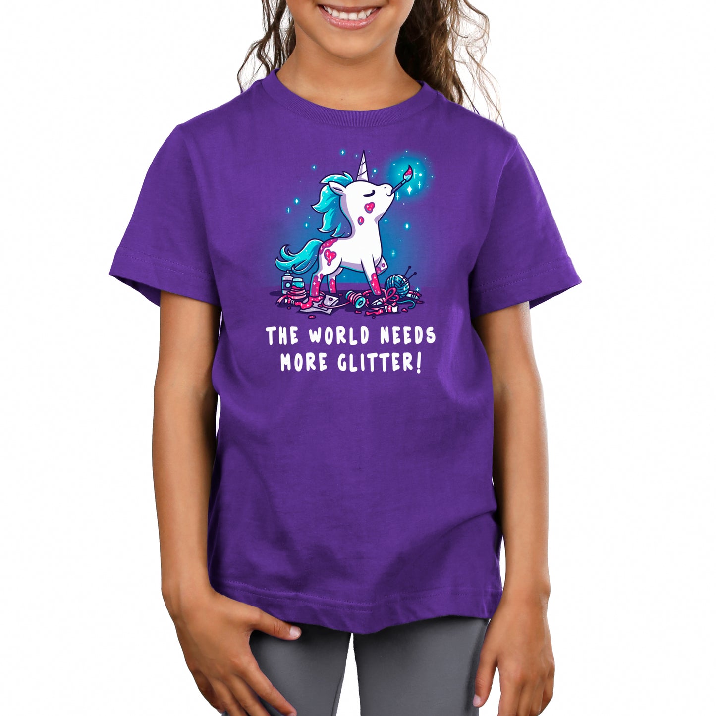 A girl wearing a glittery purple t-shirt promoting TeeTurtle's "The World Needs More Glitter" brand.