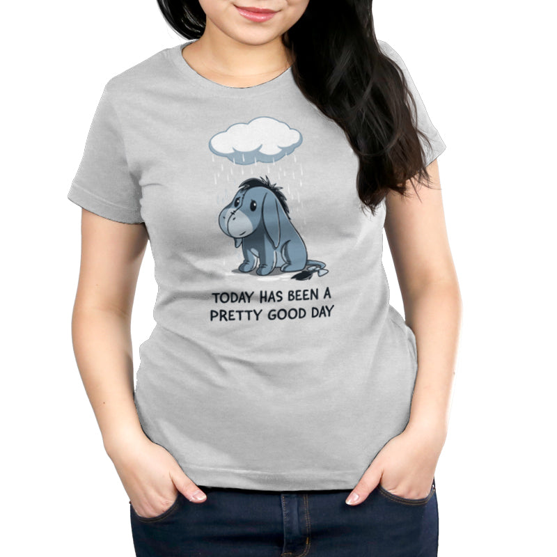 A woman wearing a Disney Officially Licensed Eeyore T-shirt made of Super Soft Ringspun Cotton, called "Today Has Been a Pretty Good Day" by Disney.