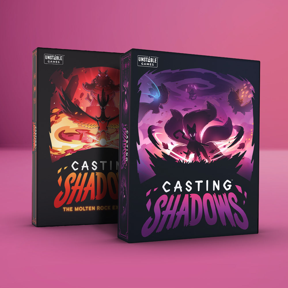 On a pink surface sit two Unstable Games masterpieces: "Casting Shadows" with its dark mystical design and "The Molten Rock Expansion" featuring a fiery theme. Kickstarter hits, these invite you to become the Ultimate Shadow Caster in an epic strategic board game adventure.